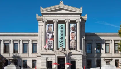 Exterior of the Museum of Fine Arts Boston. Ionic columns and a proscenium feature welcome banners with portraits of artists.