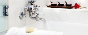 Boston boutique hotel room tub faucet with marble tile, body scrub, soap on towel and rose