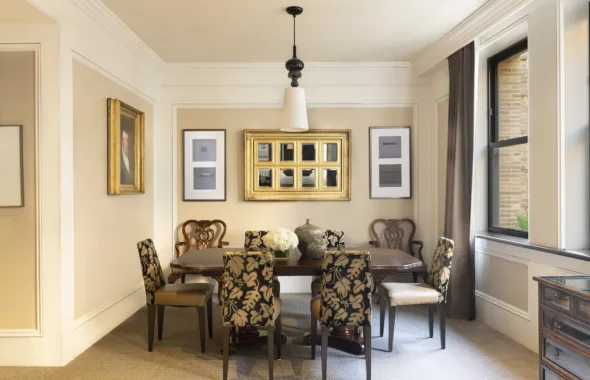 Dining room with plant-patterned chairs, oak dining table, wall art, large windows and a floral centerpiece.