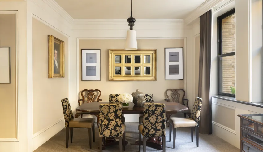 Dining room with plant-patterned chairs, oak dining table, wall art, large windows and a floral centerpiece.