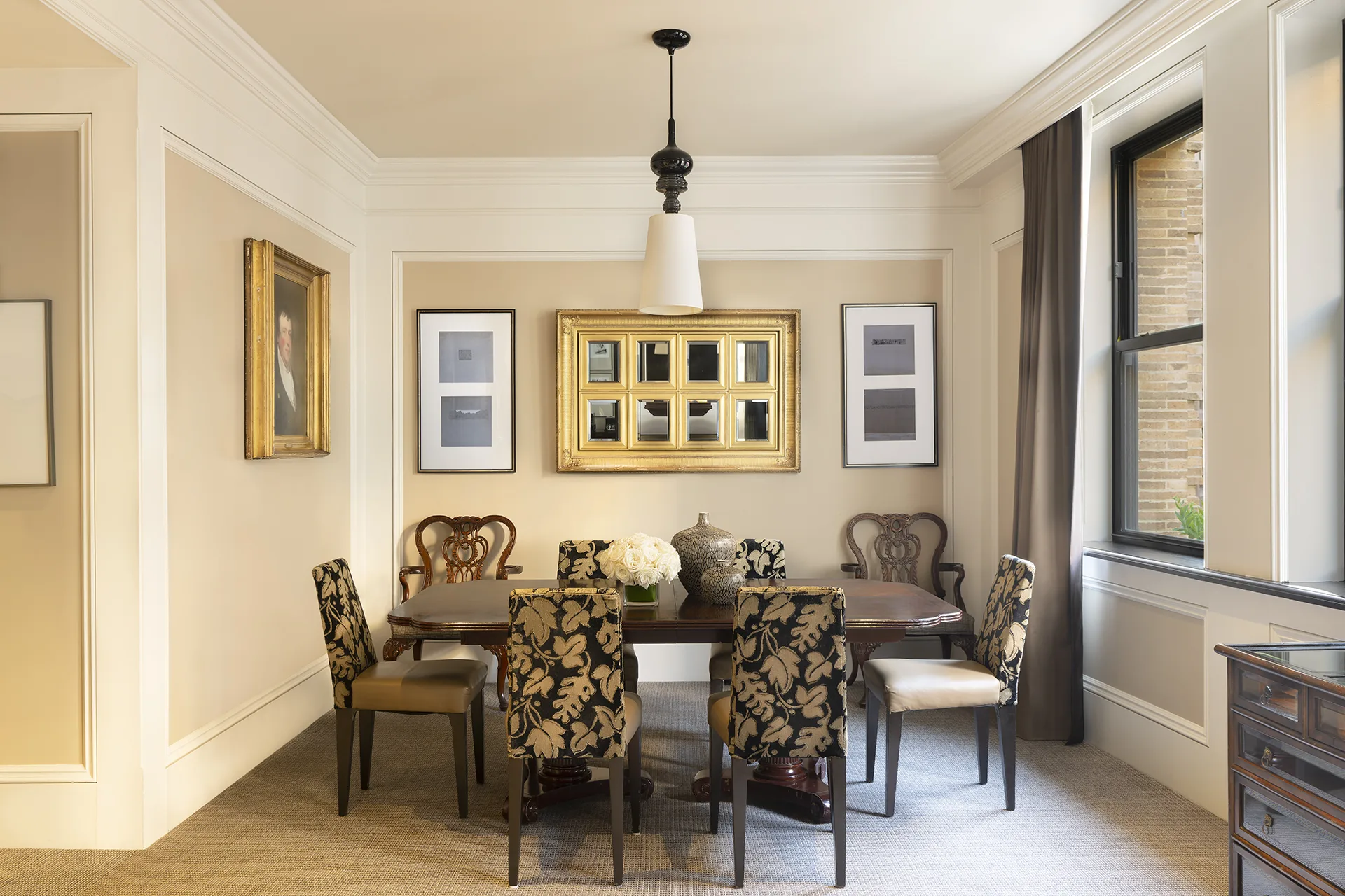 Dining room with plant-patterned chairs, oak dining table, wall art, large windows and a floral centerpiece.