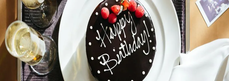 A chocolate Happy Birthday Cake alongside a bottle of champagne. This is part of our Birth Celebration Package on our website.