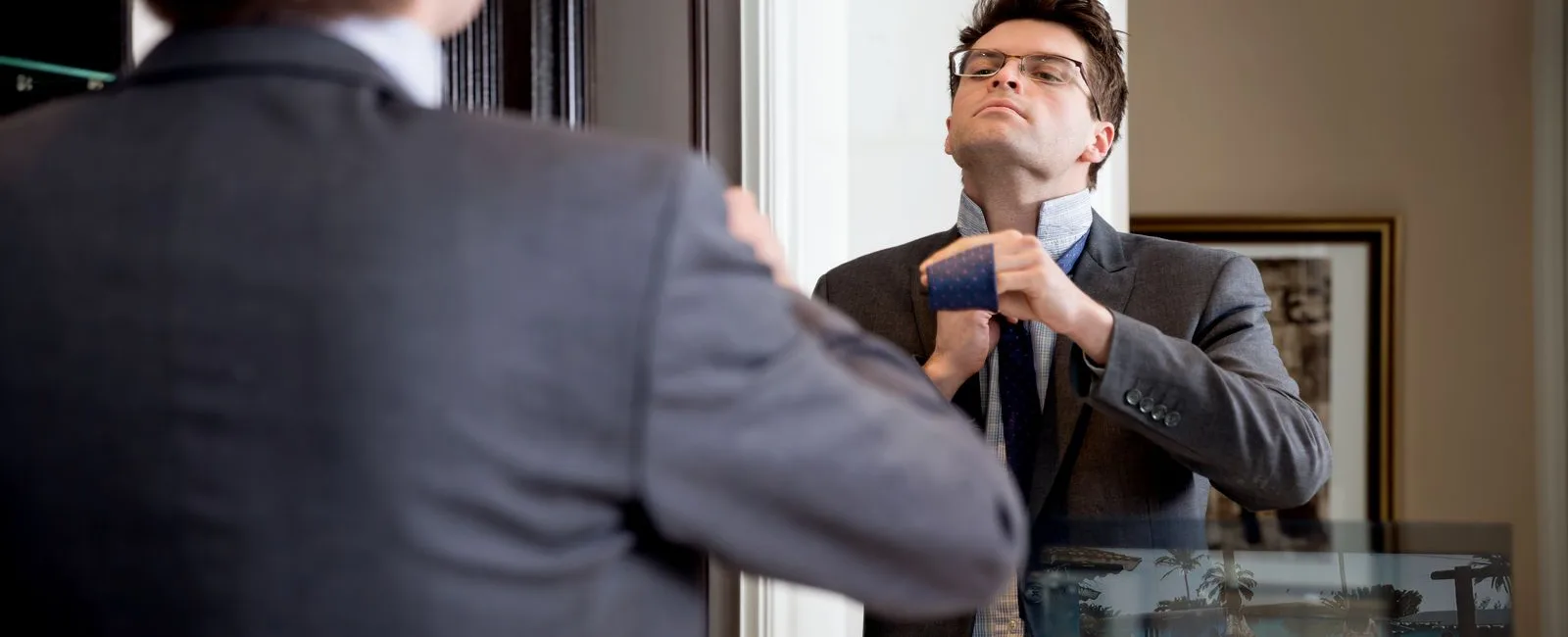 Young man is in the process of fixing his tie before heading out for his big day.