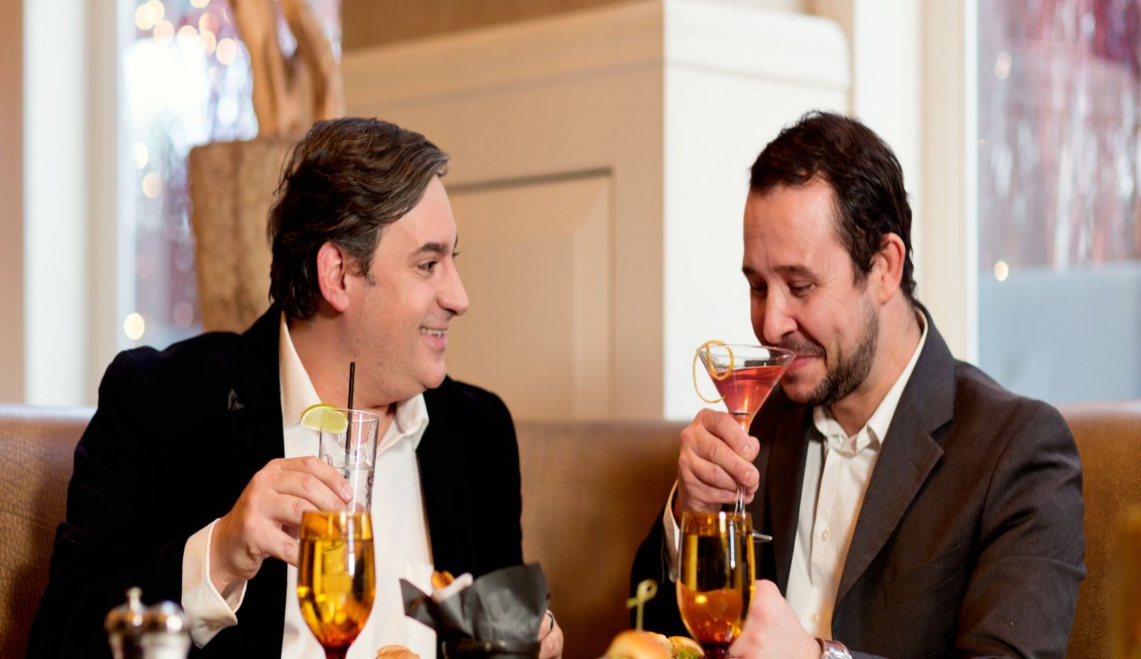 Two men enjoying cocktails in Mooo restaurant.