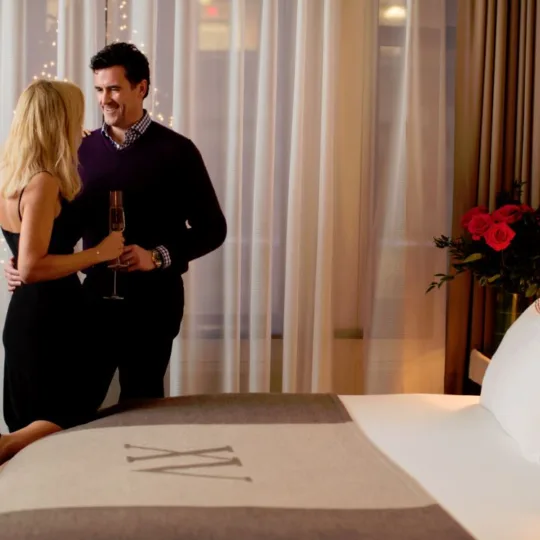 beautiful couple standing by a XV Beacon bed with roses to the side