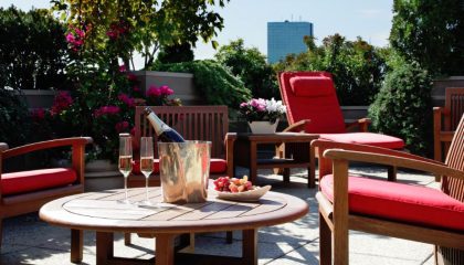 Roof deck table with red cushions featuring fresh fruit and a bottle of champagne