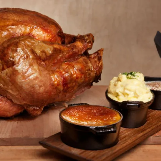 Photo of a whole Turkey and Thanksgiving sides to include; mashed potatoes, fries, and cornbread