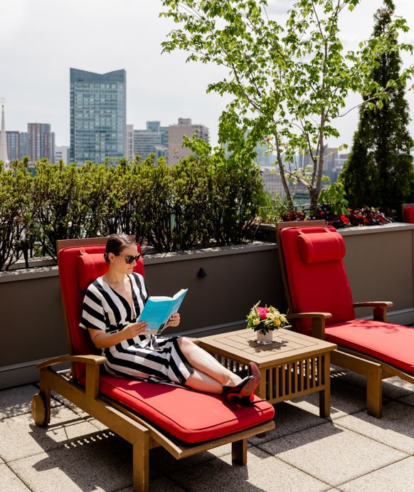 hotel guest reading on roof deck of XV Beacon Hotel