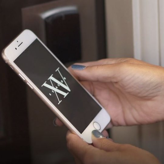 photo of an iphone with the XV Beacon Logo on the screen to showcase the mobile app opening a guestroom door.