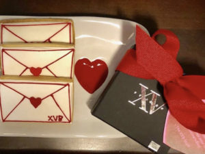 Photo of XV Beacon's Valentines Day Cookies with a small box of chocolates with a red ribbon