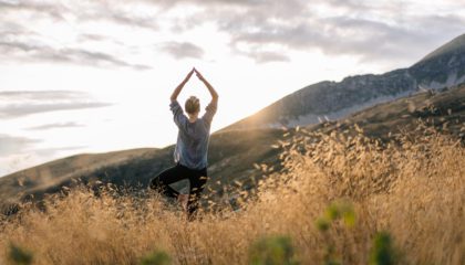 Young woman preforms yoga in mountains in morning light